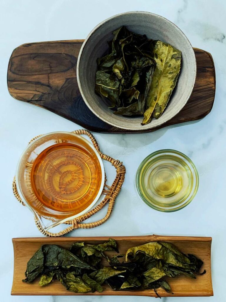 Feuilles de thé infusées, liqueur et tasse de thé vues de dessus